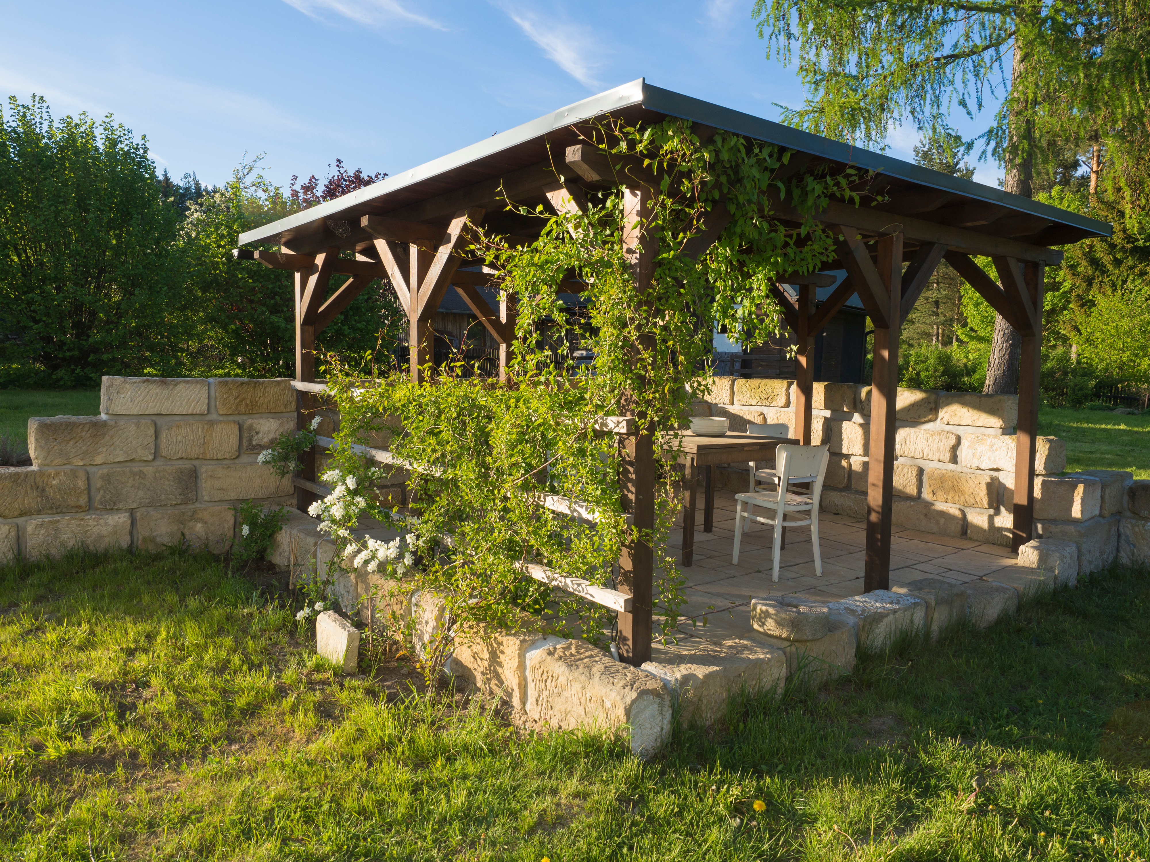 Illuminated blue lanterns hang under a pergola at dusk, creating a warm, inviting ambiance.